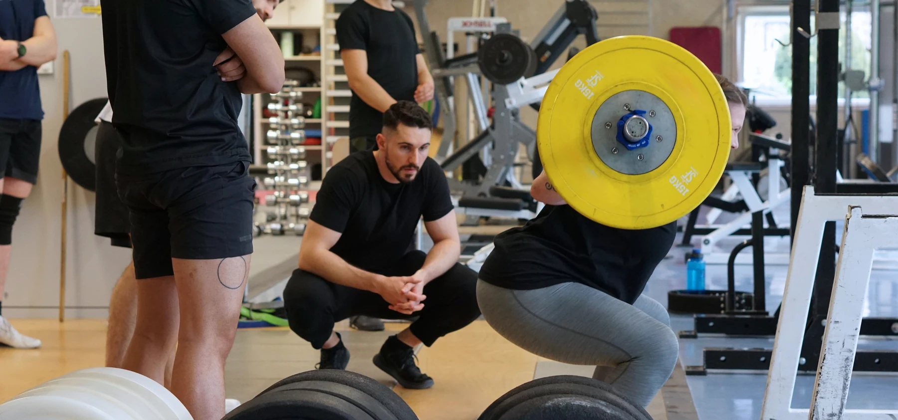 Luke Selway coaching a lifter through a squat in the gym