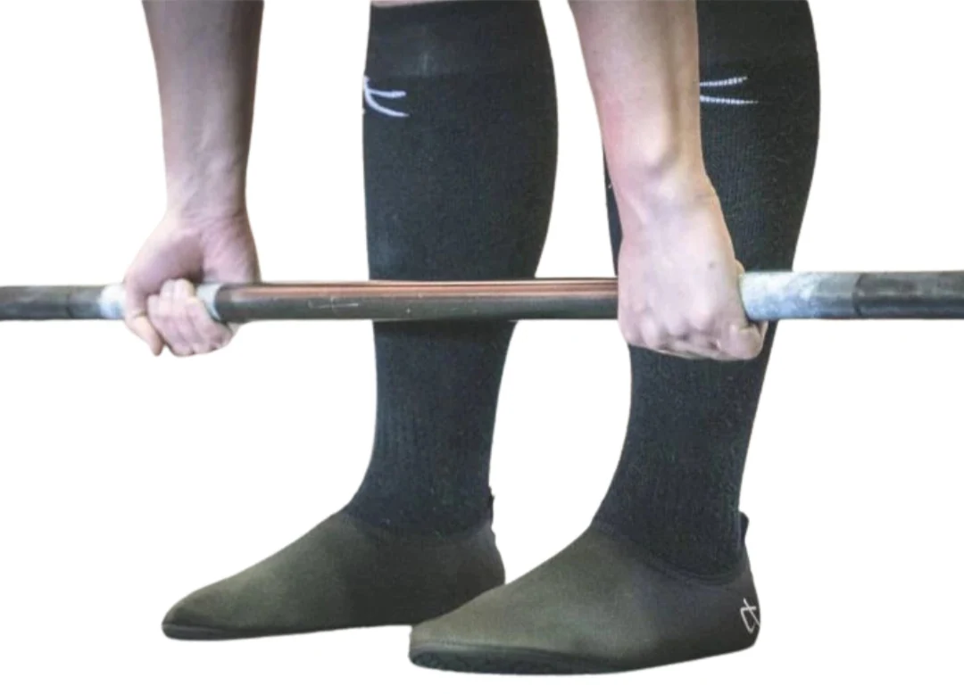 Lifter holding a barbell while wearing thin, flat deadlift slippers